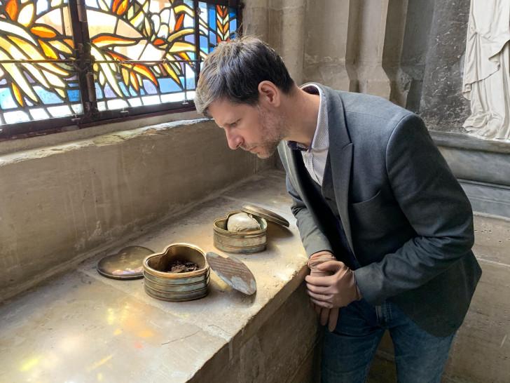 Philippe Charlier regardant l'intérieur de la boîte en métal en forme de cœur renfermant le cœur de Louis XIV